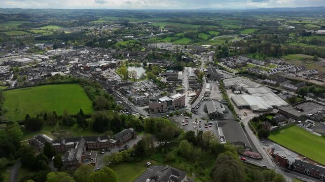 Monaghan Town, County Monaghan, Ireland, April 2024. Drone orbits counter clockwise around the Monaghan County Museum Peace Campus in a wide aerial view surrounded by fields leafy trees and buildings.