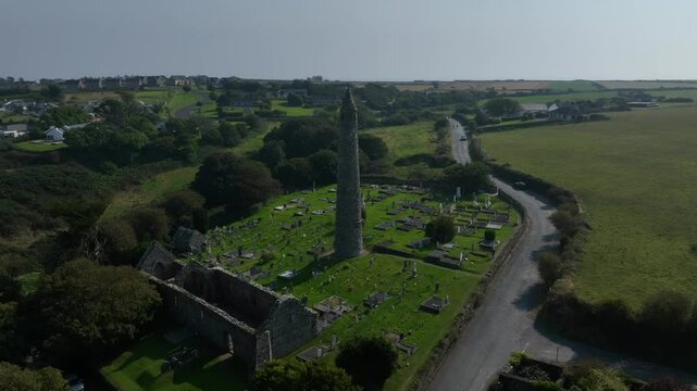 St. Declan's Monastery, Ardmore, County Waterford, Ireland, September 2024. Drone orbits counter clockwise around the historic Round Tower and graveyard with the North Atlantic Ocean in the distance.