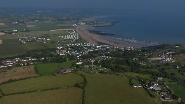 St. Declan's Monastery, Ardmore, County Waterford, Ireland, September 2024. Drone panoramic high angle overview orbits clockwise above the Cathedral ruins and Round Tower centered on a hazy day.