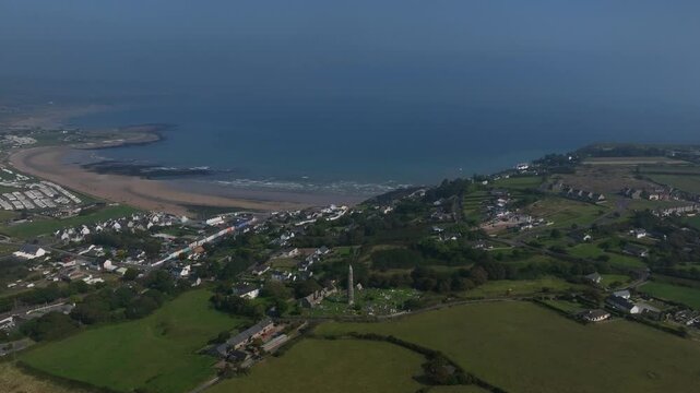 St. Declan's Monastery, Ardmore, County Waterford, Ireland, September 2024. Drone orbits clockwise in panoramic overview of the Round Tower and Village on the North Atlantic Ocean coastline.