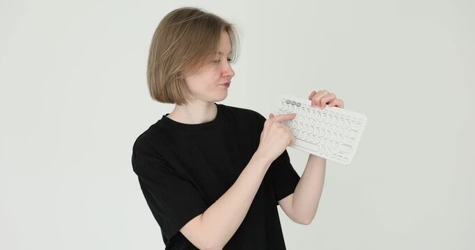 Woman demonstrates a compact white keyboard against plain white background