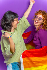 Obraz premium Happy lesbian couple dancing wrapped with lgbt rainbow flag