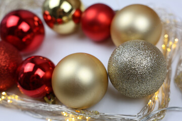 Christmas balls of red and gold color lie inside a New Year's garland of gold color on a white background. The concept of Christmas, New Year and Holiday. High quality photo