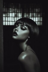 A pale skinned model with bold make-up, chin length haircut, in dark studio. smokey make-up. Fashion. Hairstyle. Cosmetics. Style. Black and white.	
