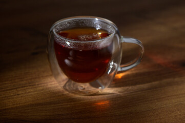 A steaming cup of herbal tea resting on a wooden table in the warm glow of afternoon sunlight