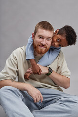 Vertical portrait shot of happy adoptive father holding hands with adorable little Black boy while...