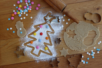 Gingerbread dough with cookie cutters  and Christmas tree drawn on flour on wooden table - Powered by Adobe