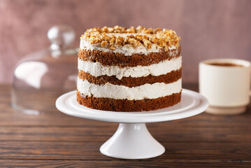 Pumpkin or carrot cake with coconut cream and walnut with cup of tea on wooden background. Vegan dessert, sugar, gluten and lactose free.