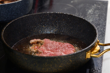 Sizzling steak cooking in a frying pan on a modern stovetop in a cozy kitchen setting