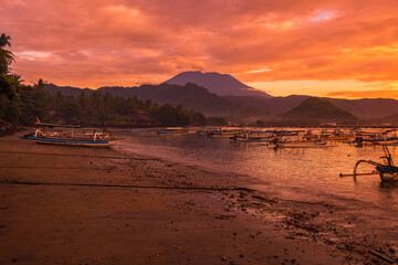 Sunset or sunrise with Agung volcano and quiet ocean with local fishing boats in Bali