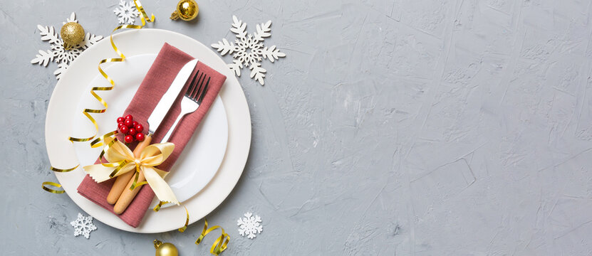Christmas table place setting with christmas decor and plates, kine, fork and spoon. Christmas holiday background. Top view with copy space