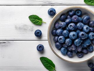 Taz&oacute;n de ar&aacute;ndanos frescos sobre mesa de madera blanca con hojas de menta