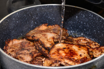 Juicy pork chops sizzling in a frying pan while water is added for a flavorful cooking experience
