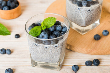 Healthy breakfast or morning with chia seeds vanilla pudding and blueberry berries on table background, vegetarian food, diet and health concept. Chia pudding with coconut milk and blueberry