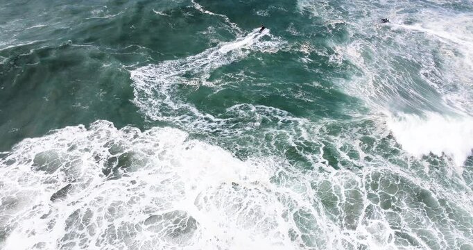 Aerial drone shot of jet ski rider in the Atlantic Ocean on a day with giant waves in Nazare, Portugal, Europe. Big wave surfing town. Shot in ProRes 422 HQ Log
