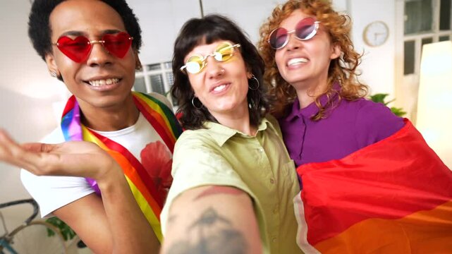 Multi-ethnic young lbgt people dancing waiving rainbow flag celebrating at home