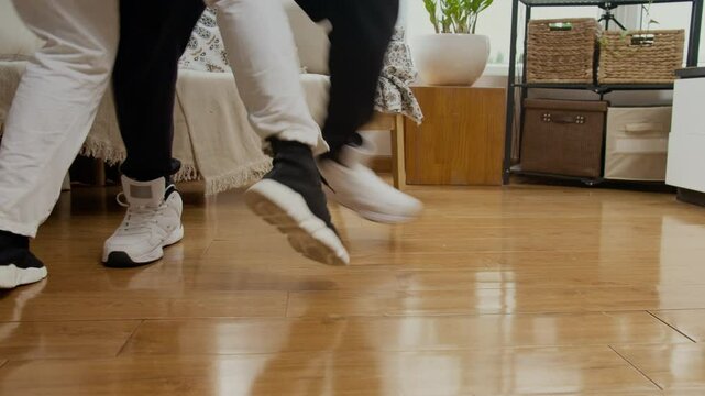 Tilt up shot of diverse couple in activewear having dance rehearsal in living room