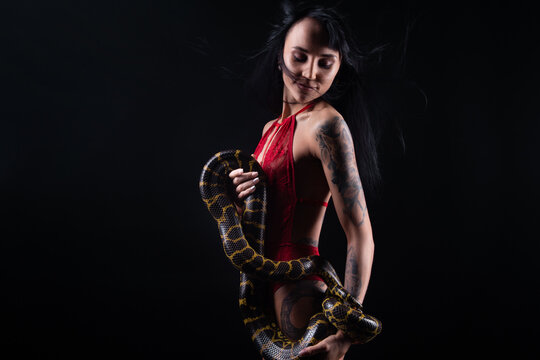 Image of brunette woman with blowing hair holding snake