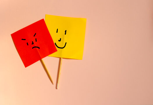 Red paper flags with angry face and yellow with happy face concept of mood and bipolarity