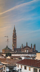 Naklejka premium Cremona duomo cathedral towers over the city, blending with rooftops and buildings against blue sky