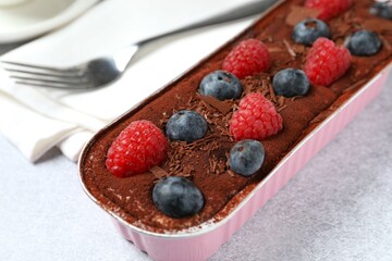 Delicious tiramisu cake with berries on table