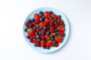 Different fresh ripe berries in bowl on the table, top view