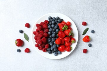 Different fresh ripe berries in bowl on the table, top view