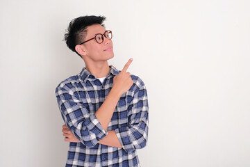 Young Asian man staring and pointing beside him with happy expression