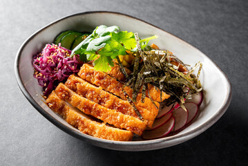 A bowl of grilled chicken, sliced cucumbers, red cabbage, herbs, radishes, and seaweed on a textured grey surface. Perfect for healthy eating, food blogs, or culinary websites