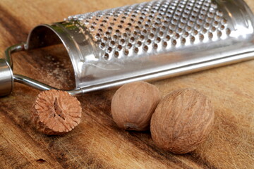 Muskatnuss mit und ohne Schale, Muskatnüsse, Gewürz, Nuss, Makro, Küchenreibe, Reibe, Holz, Brett, Tisch, Metall, Essen, gesund, braun, Küche, Reibe, halbiert, kochen, Gegenstand