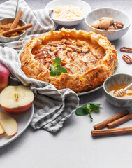 Delicious apple pie with almonds, honey, and cinnamon served on a table with fresh apples and nuts