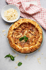 Delicious homemade apple galette with almond flakes and fresh mint on table