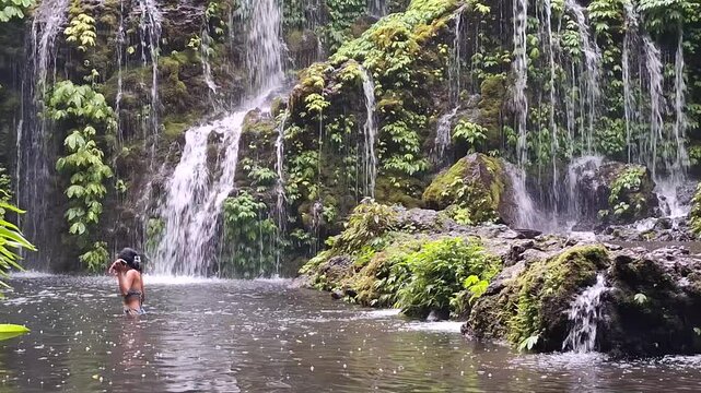 A majestic tropical waterfall cascading down into a serene pool surrounded by lush greenery