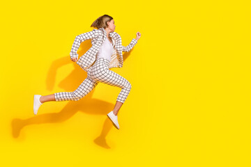 Full body photo of attractive young woman running have fun dressed stylish white plaid clothes isolated on yellow color background
