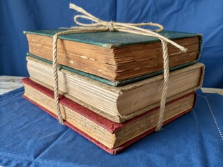 Vintage Stack of Colorful Wooden Books Bound with Tan Rope on Blue Background, Perfect for Product Photography with Ample Copy Space for Branding and Design Use