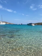 Crystal-clear waters of a Sardinian bay, showcasing anchored yachts and boats with rocky shores in...