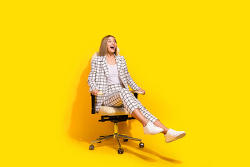 Excited young businesswoman enjoying her work, spinning joyously on an office chair against a...