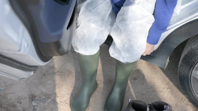 Person putting on waterproof boots over PPE, after the DANA storm in Valencia