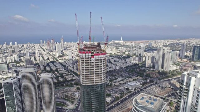a drone shot of a building in construction with cranes next to arlozorov interchange tel aviv