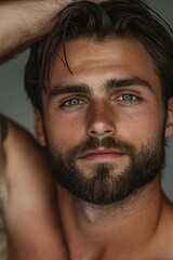 Fototapeta premium Portrait of a young man with a beard and deep blue eyes in soft lighting