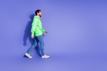 Naklejka premium Full size photo of pretty young male profile walking empty space wear trendy green outfit isolated on purple color background