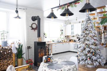 Christmas decor in white kitchen with burning stove fireplace, festive mess, village interior with a snowy Christmas tree. New Year, Christmas mood, cozy home.