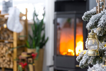 Metall black stove, burning hearth fireplace in white Festive interior of house is decorated for Christmas and New Year, Christmas tree. firewood in the woodpile, cozy and heating of home