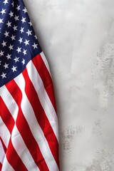 A partial view of the American flag displaying the blue field with white stars and red and white stripes in a textured fabric design set against a rough white surface with copy space.