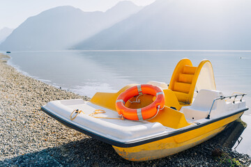 A small white catamaran on the water near the shore.