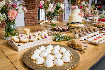 An exquisite dessert table adorned with a selection of artisanal pastries and cakes. The setup includes donuts, mousse cakes, mini cheesecakes, and layered desserts, all elegantly presented on rustic 