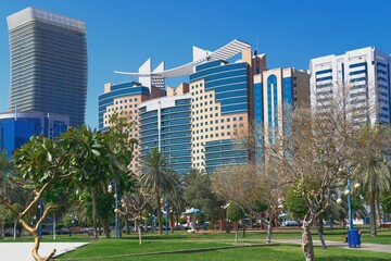 Cityscape with beautiful landscaped Green public park with palm trees against modern residential buildings in Abu Dhabi, UAE