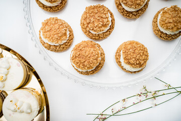 A top-down view of delicate cream-filled choux pastries with a crunchy topping, arranged on a glass stand. The elegant presentation emphasizes the texture and detail of each pastry.
