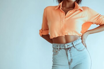 A woman posing in an orange shirt and jeans, looking directly at the camera