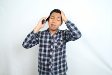 unhealthy asian man with migraine and fatigue calling health care using smartphone isolated on white wearing casual shirt